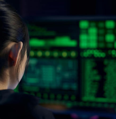 Analista de ciberseguridad monitoreando múltiples pantallas con código de seguridad